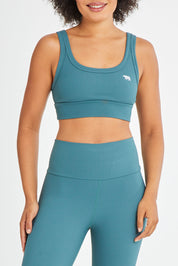 Model Olivia wearing size 10 of the Scoop It Up Sports Bra in colour Sage (Green), from the front, cropped image
