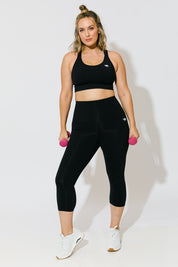 Model Jess wearing size 14 of the Lotus Trio Long Line Sports Bra in colour Black (Black), from the front, showing the whole outfit