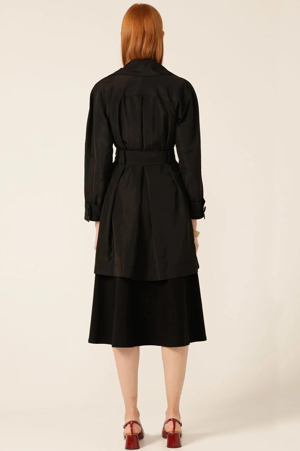 A model wearing the Noir Trench in colour Black (Black), from the back