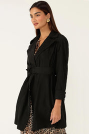 A model wearing the Noir Trench in colour Black (Black), from the front, cropped image