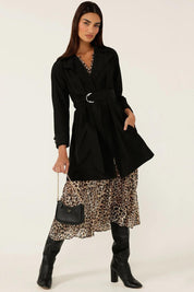 A model wearing the Noir Trench in colour Black (Black), from the front, showing the whole outfit