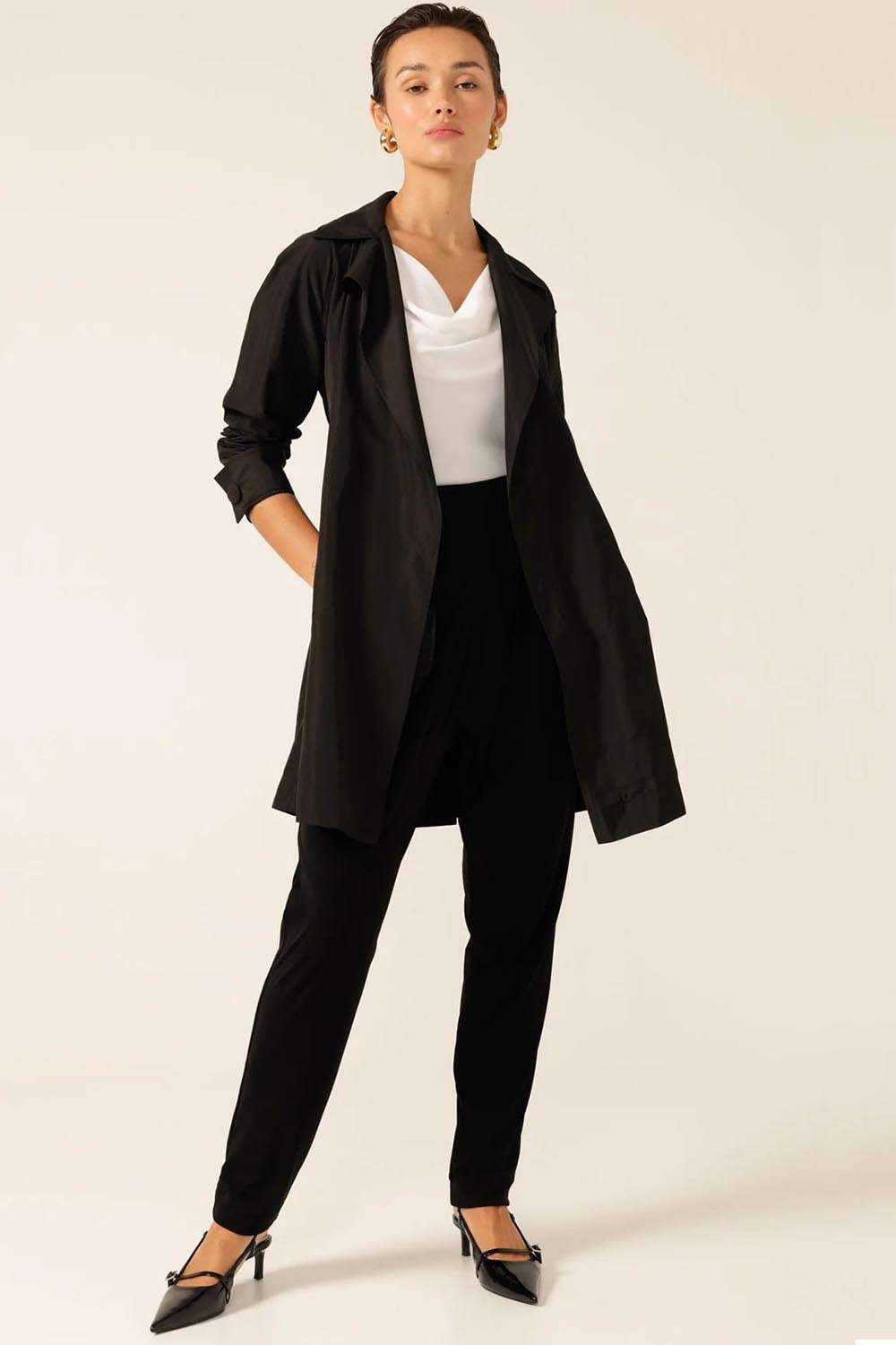 A model wearing the Noir Trench in colour Black (Black), from the front, showing the whole outfit