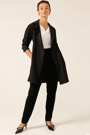 A model wearing the Noir Trench in colour Black (Black), from the front, showing the whole outfit