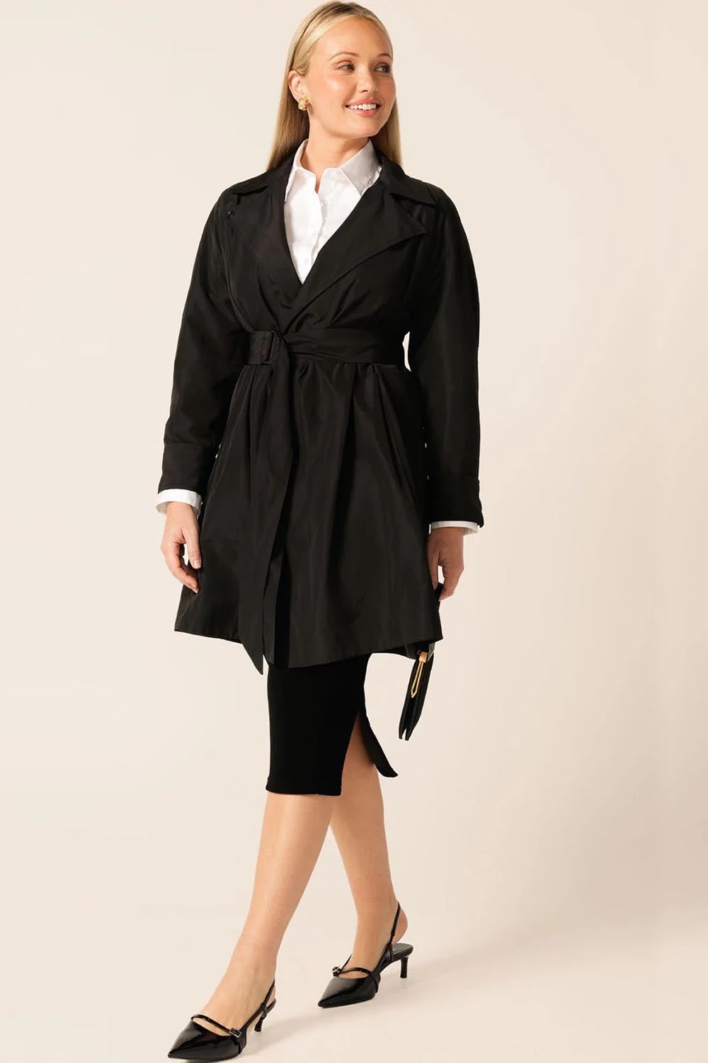 A model wearing the Noir Trench in colour Black (Black), from the front, showing the whole outfit