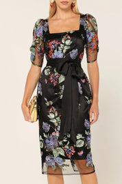 A model wearing the Mont Tombe Dress in colour Floral (Black), from the front, cropped image