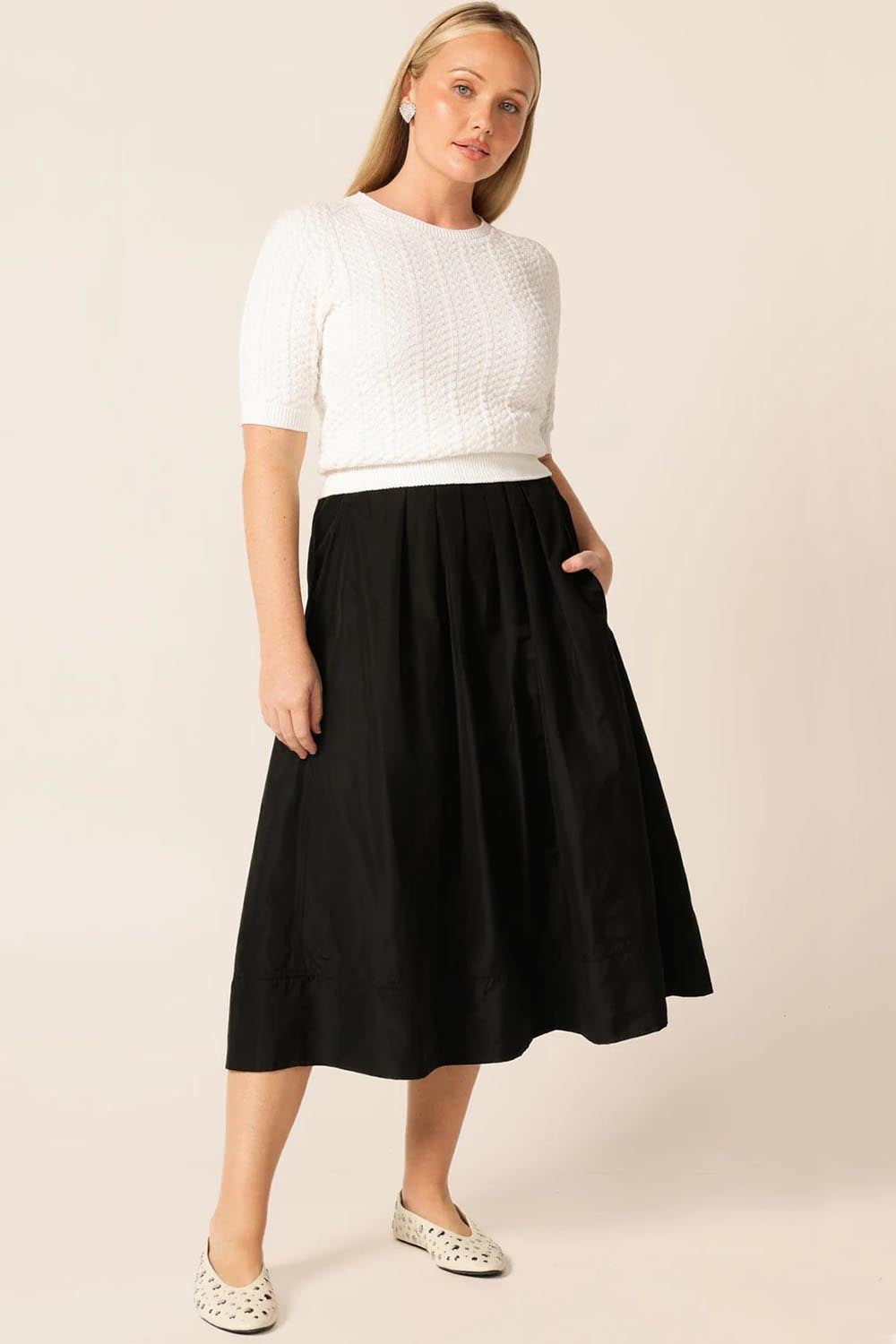 A model wearing the Pleated Ain colourLine Skirt - Black (Black), from the front, showing the whole outfit