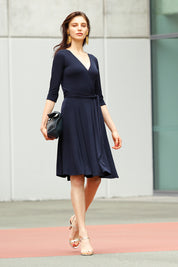 A model wearing the Reverse Wrap Full Skirt Dress in colour Navy (Blue), from the front, showing the whole outfit
