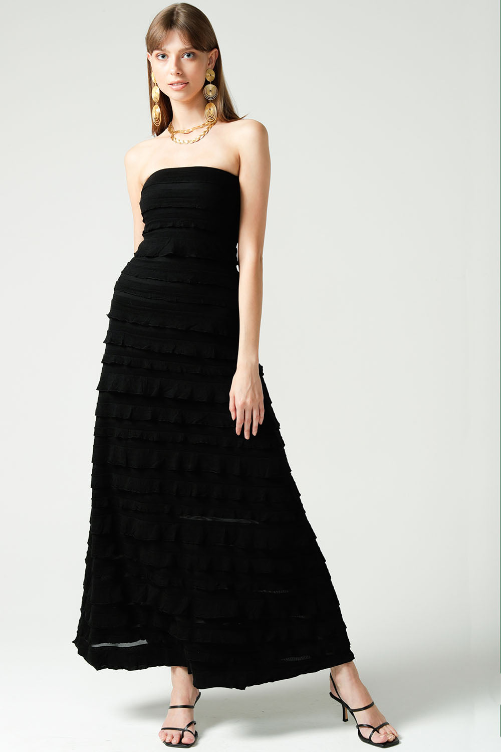 A model wearing the Maddison Maxi Ruffle Dress in colour Black (Black), from the front, showing the whole outfit