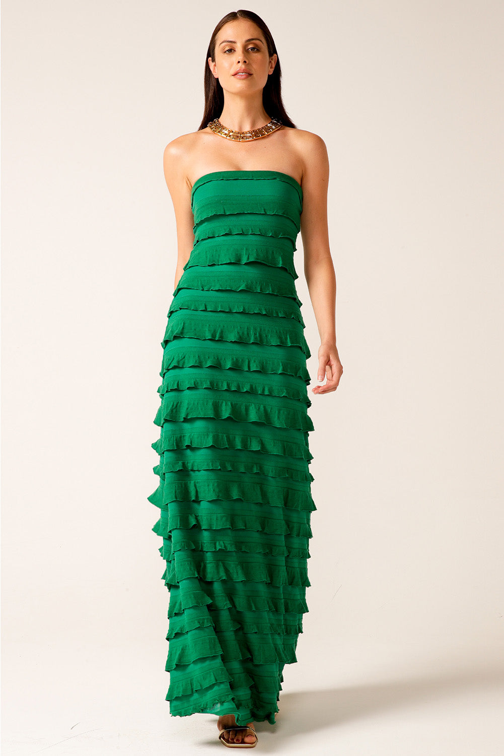 A model wearing the Maddison Maxi Ruffle Dress in colour Emerald (Green), from the front, showing the whole outfit
