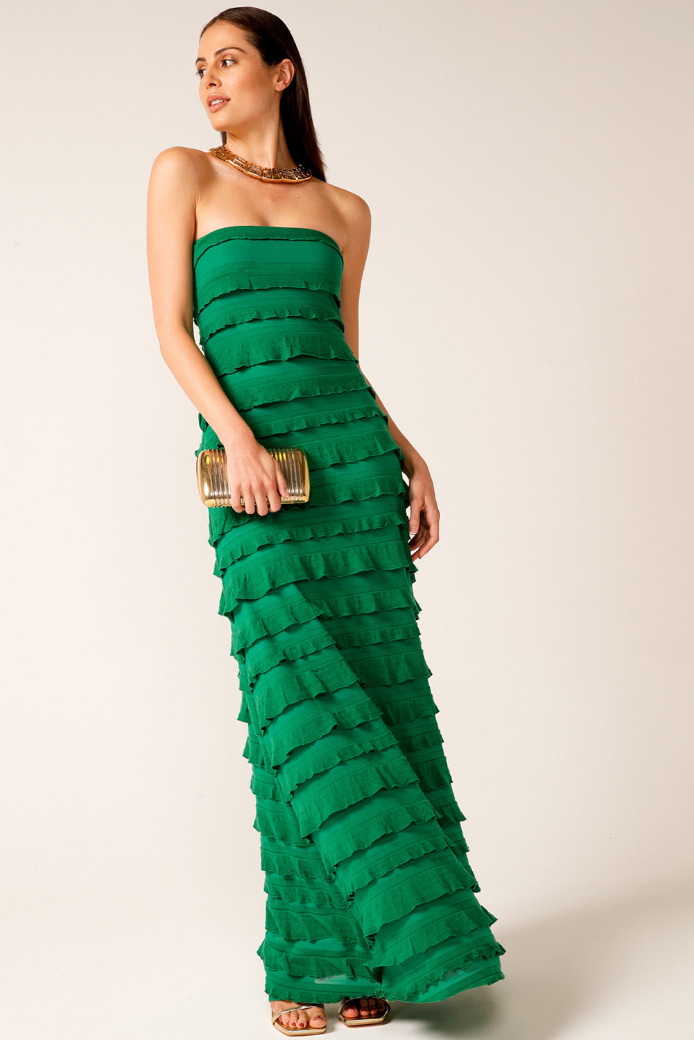 A model wearing the Maddison Maxi Ruffle Dress in colour Emerald (Green), from the front, showing the whole outfit