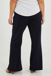 Model Maddy wearing size 16 of the Classic Trouser in colour Navy (Blue), from the back