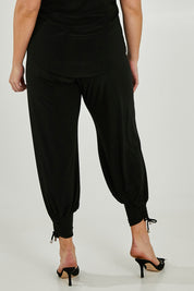 Model Maddy wearing size 16 of the Harem Pant in colour Black (Black), from the back