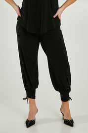 Model Maddy wearing size 16 of the Harem Pant in colour Black (Black), from the front, cropped image