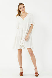A model wearing the Gia Dress in colour Natural, from the front, showing the whole outfit