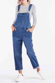 A model wearing the Simone Dungaree in colour Wornwash (Blue), from the front, cropped image