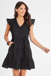 Model Madeline wearing size 10 of the Alina Tiered Linen Dress in colour Black (Black), from the front, cropped image