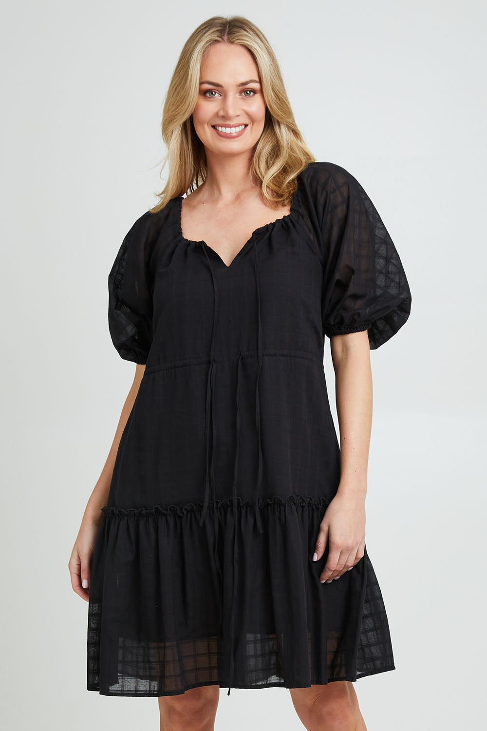 Model Grace wearing size 10 of the Ruby Tiered Midi Dress in colour Black (Black), from the front, cropped image