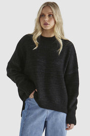 A model wearing the Kirsha Jumper in colour Black (Black), from the front, cropped image