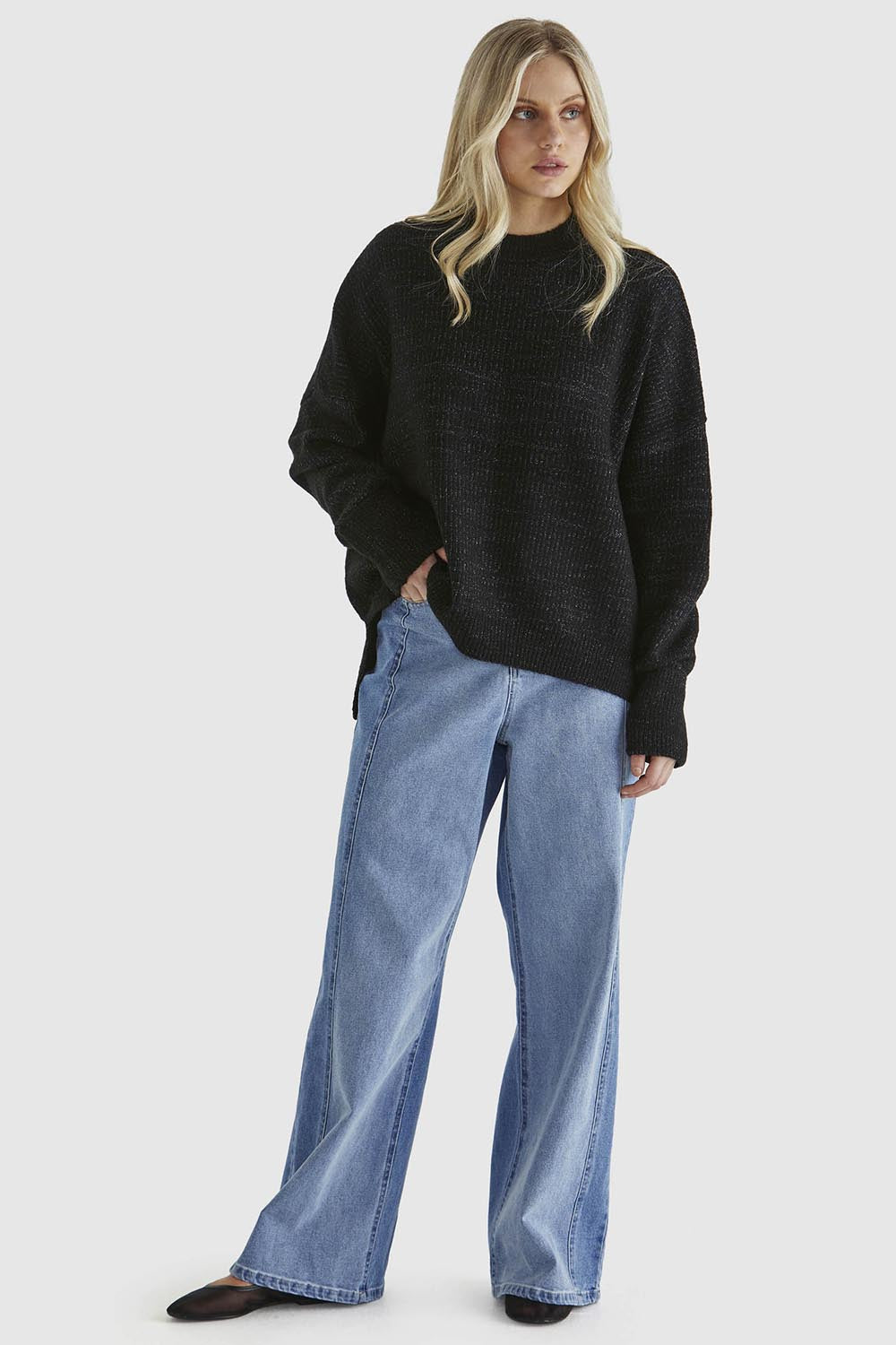 A model wearing the Kirsha Jumper in colour Black (Black), from the front, showing the whole outfit