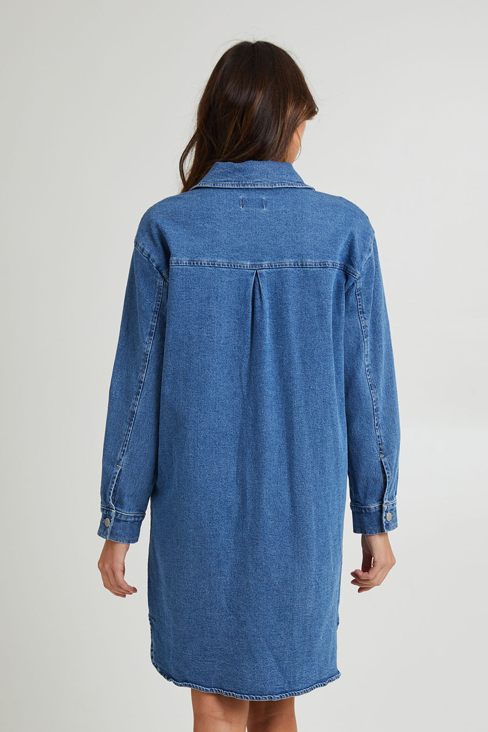 Model Madeline wearing size 10 of the Nya Long Denim Shacket Dress in colour 80Wash (Blue), from the back