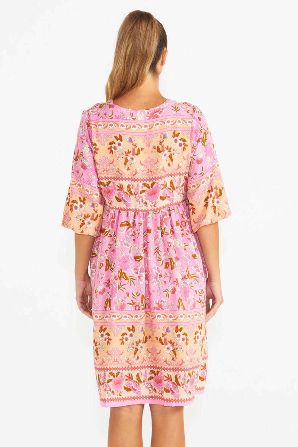 A model wearing the Chiara Dress in colour Paisley (Pink), from the back
