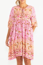 A model wearing the Chiara Dress in colour Paisley (Pink), from the front, cropped image
