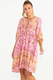 A model wearing the Chiara Dress in colour Paisley (Pink), from the front, cropped image
