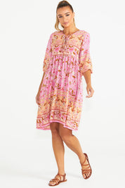 A model wearing the Chiara Dress in colour Paisley (Pink), from the front, showing the whole outfit
