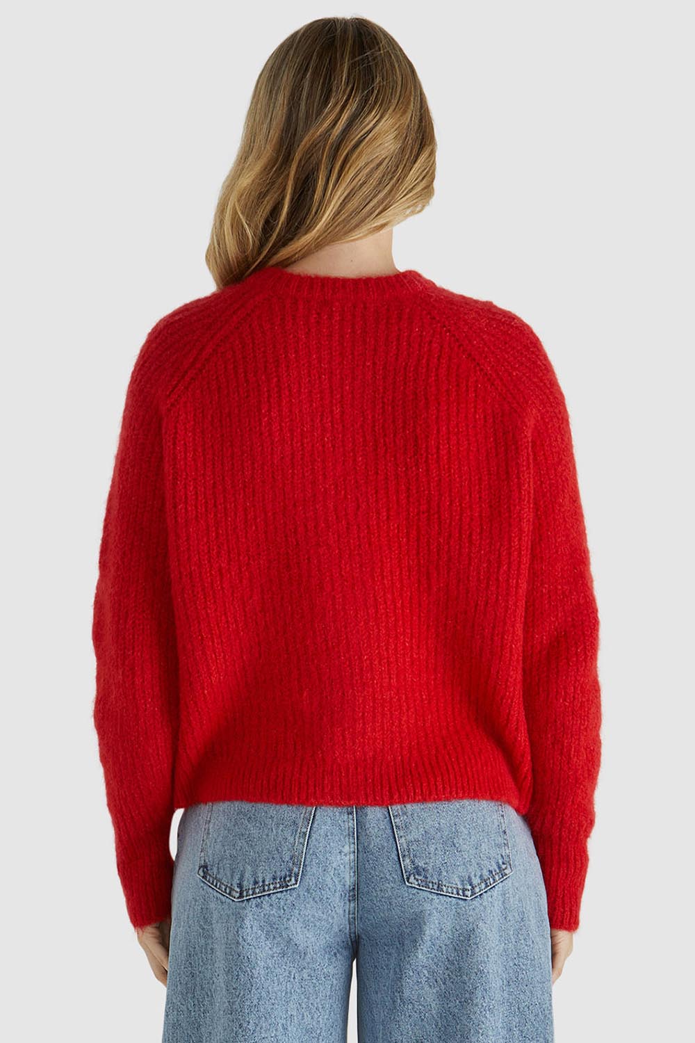 A model wearing the Romee Cardi in colour Poppyred (Red), from the back