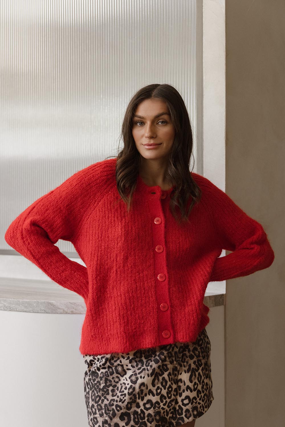 A model wearing the Romee Cardi in colour Poppyred (Red), from the front, showing the whole outfit