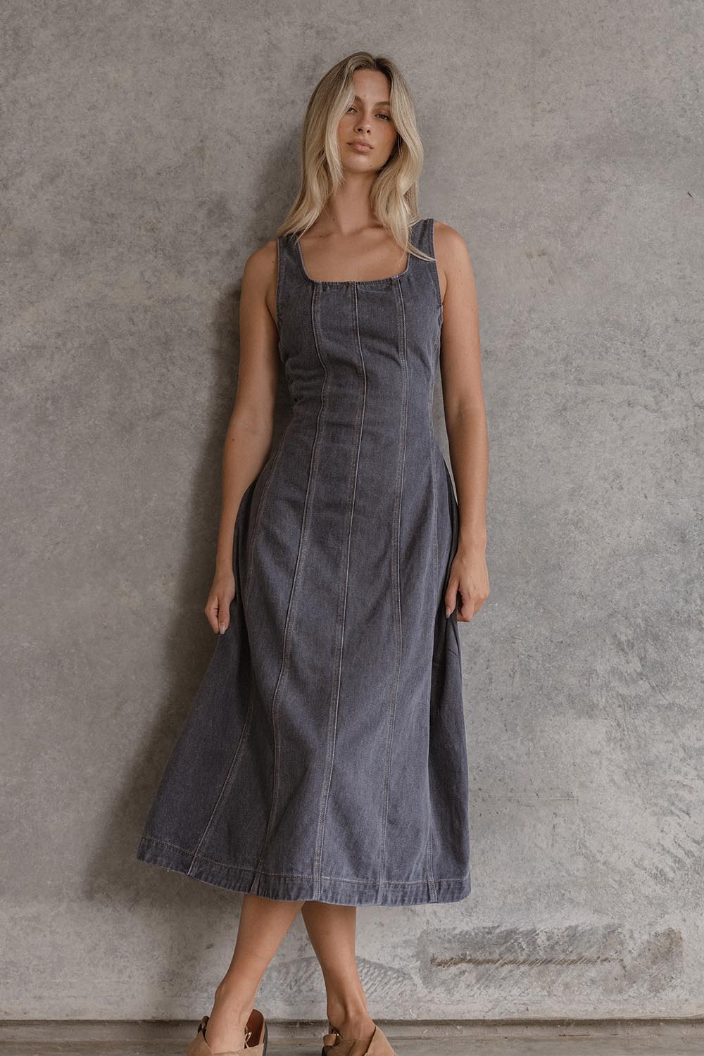 A model wearing the Ainsley Dress in colour Darkdenim (Black), from the front, showing the whole outfit