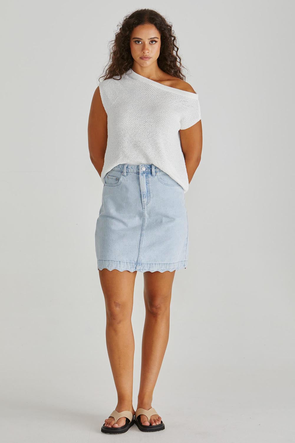 A model wearing the Vale Scalloped Denim Skirt in colour Bleach (Blue), from the front, showing the whole outfit