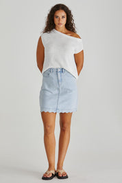 A model wearing the Vale Scalloped Denim Skirt in colour Bleach (Blue), from the front, showing the whole outfit