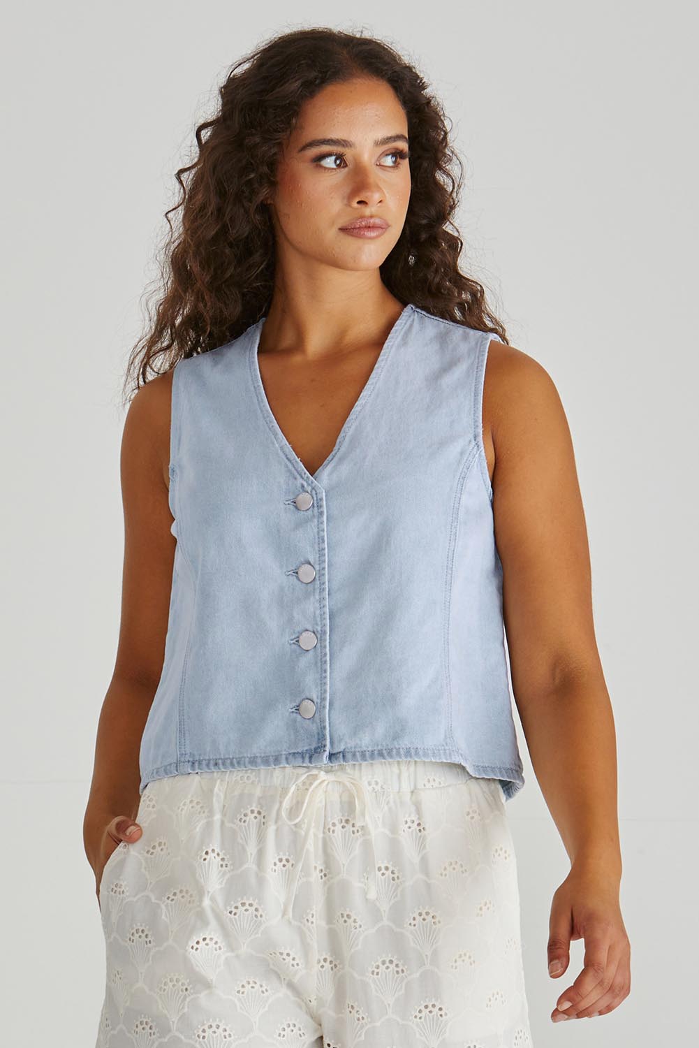 A model wearing the Sabine Denim Vest in colour Bleach (Blue), from the front, cropped image