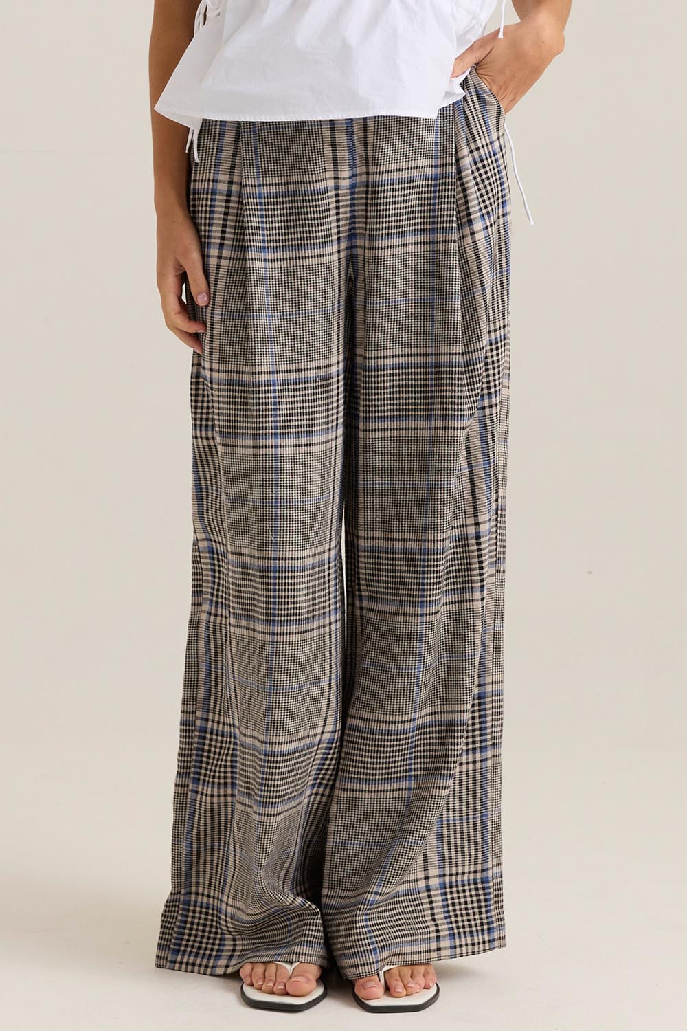 A model wearing the Blakely Pant in colour Check (Grey), from the front, cropped image