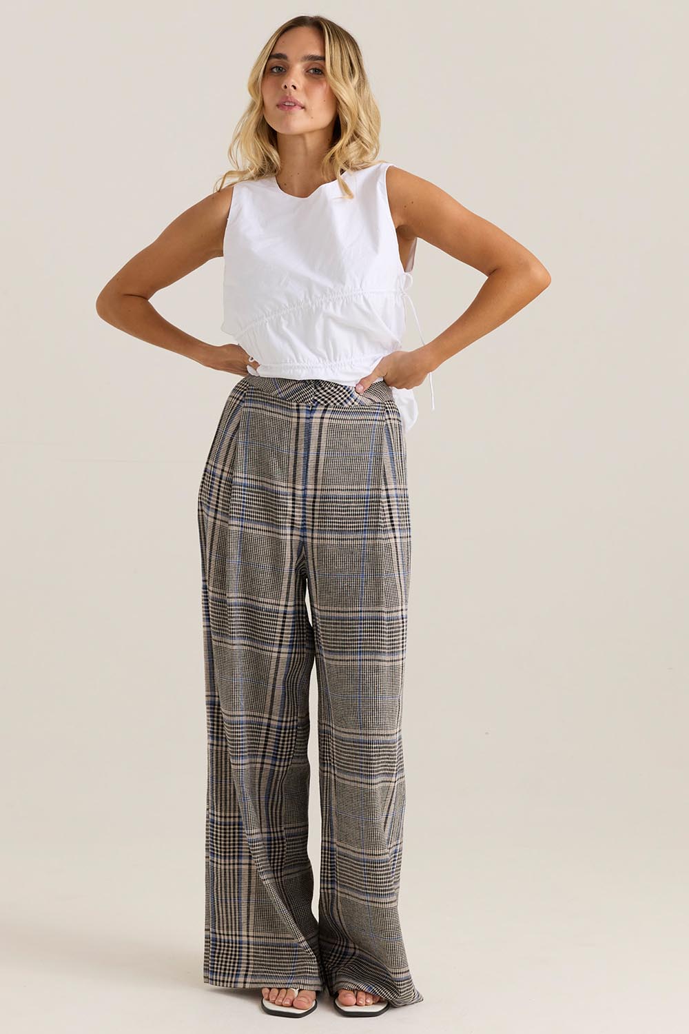 A model wearing the Blakely Pant in colour Check (Grey), from the front, showing the whole outfit