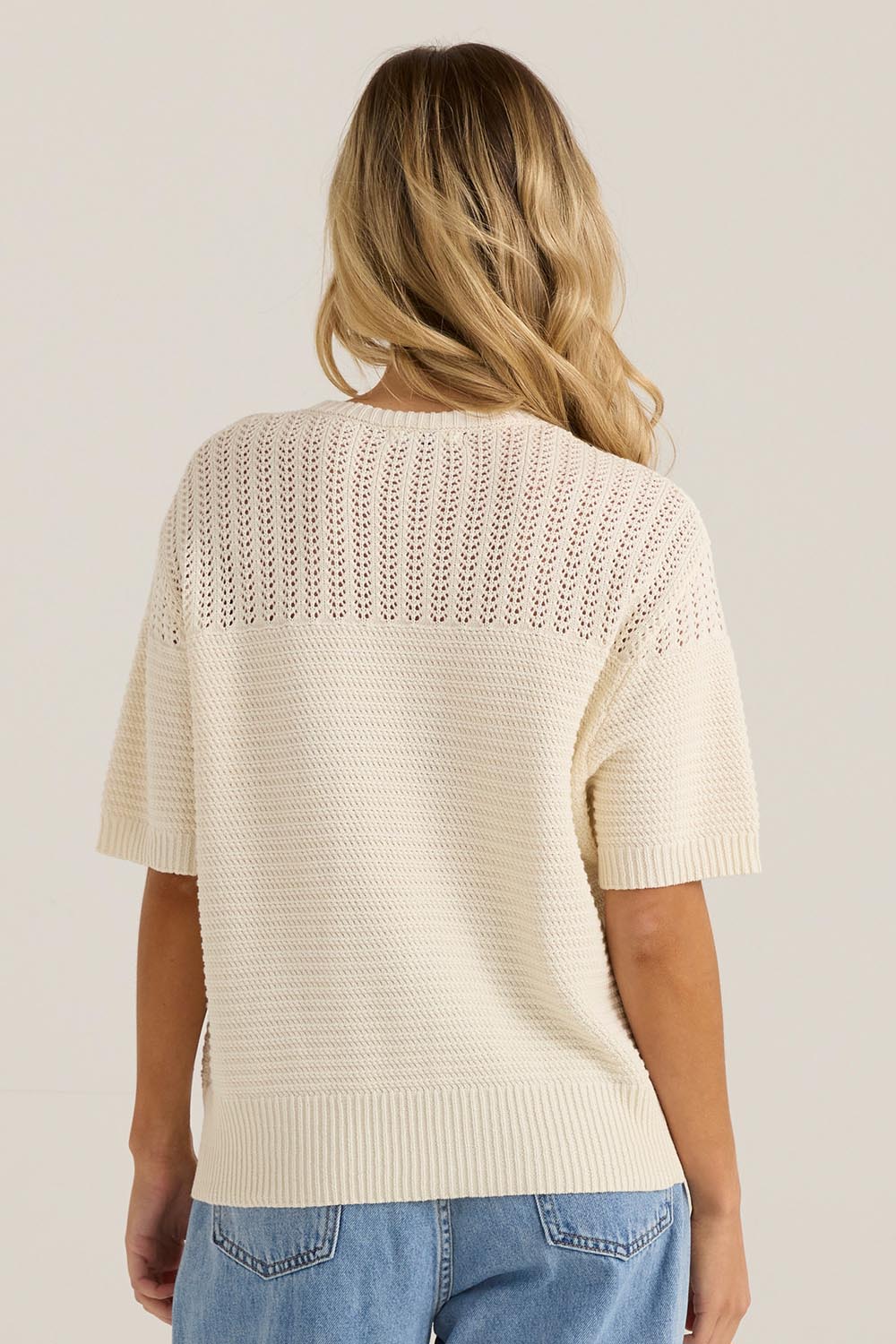A model wearing the Cherri Top in colour Cream, from the back