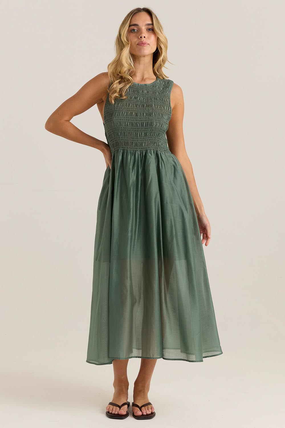 A model wearing the Saga Tank Dress in colour Sageolive (Green), from the front, showing the whole outfit