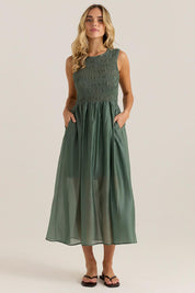 A model wearing the Saga Tank Dress in colour Sageolive (Green), from the front, showing the whole outfit