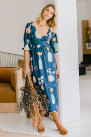 Model Phoebe wearing size 10 of the Romantik Dress in colour Vases (Blue), from the front, showing the whole outfit