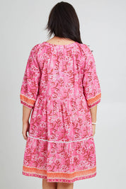 Model Poppy wearing size 16 of the Sandy Bay Dress in colour Pinkorange (Pink), from the back