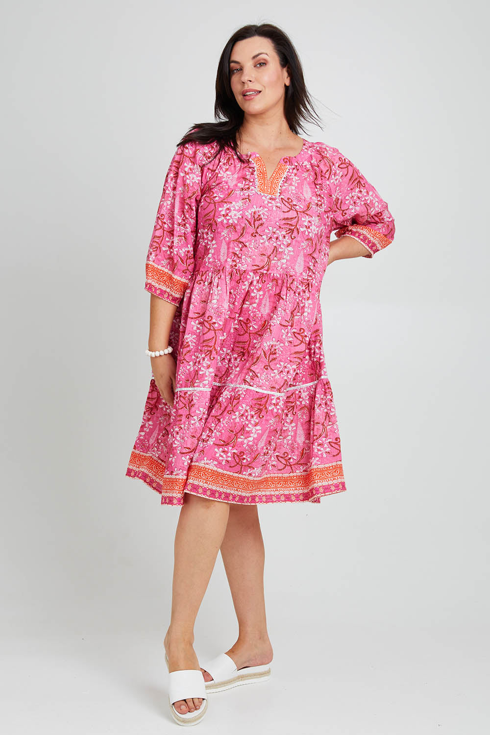 Model Poppy wearing size 16 of the Sandy Bay Dress in colour Pinkorange (Pink), from the front, showing the whole outfit