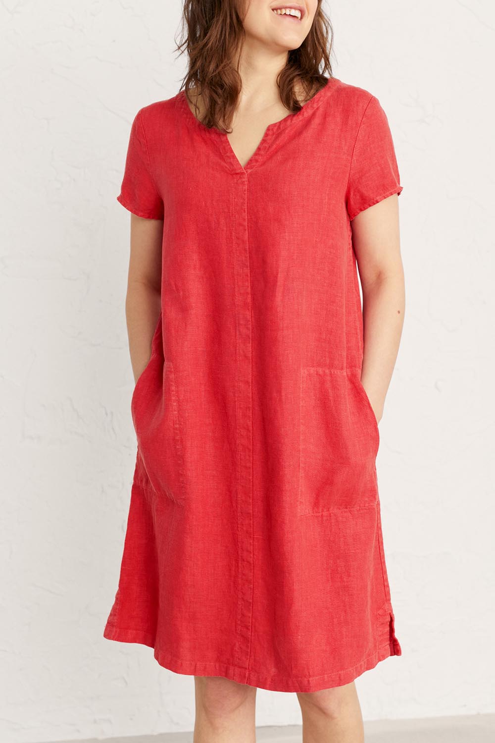 A model wearing the Okanum Dress in colour Squash (Red), from the front, cropped image