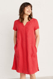 A model wearing the Okanum Dress in colour Squash (Red), from the front, cropped image