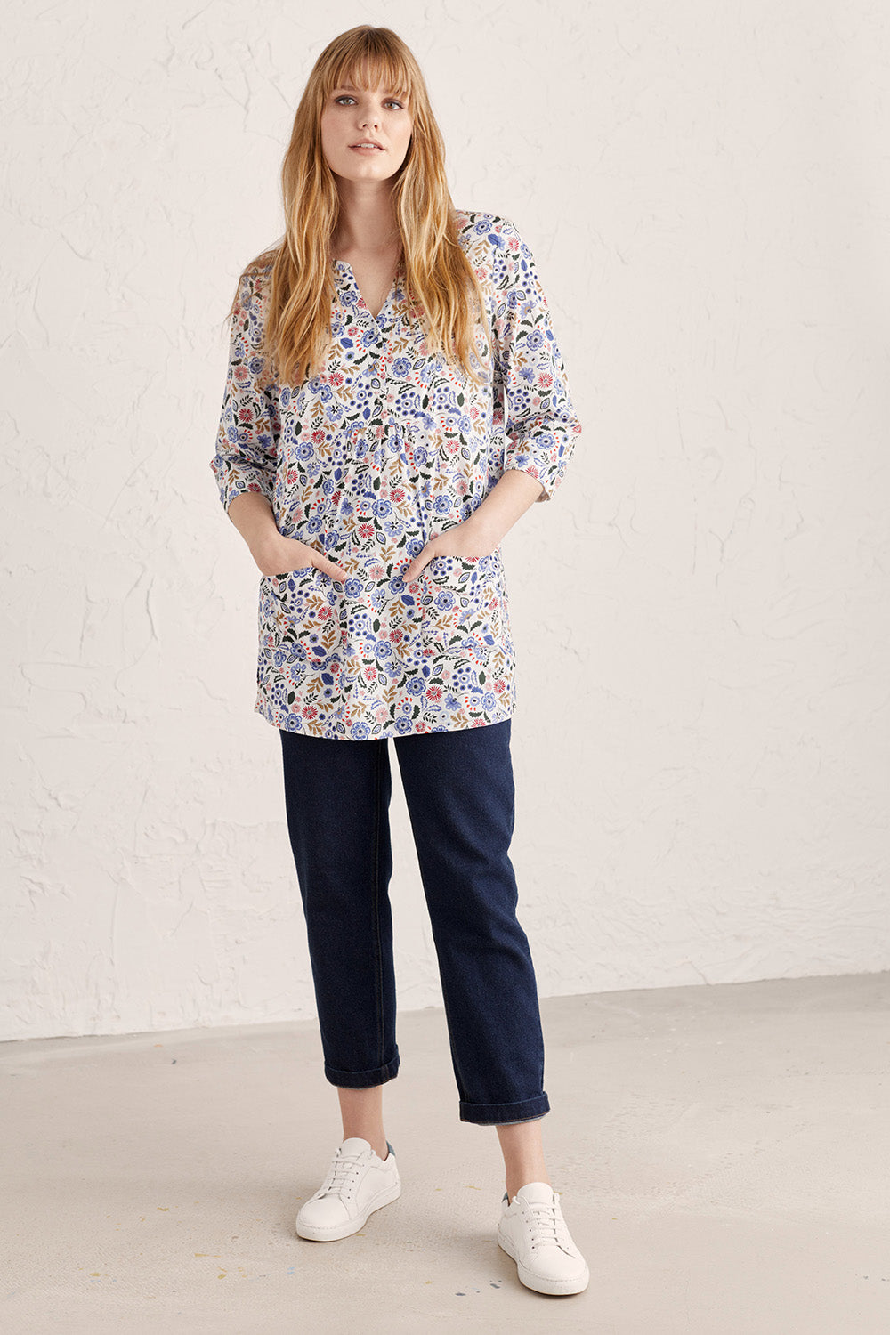 A model wearing the Adventurier Tunic in colour Floral (White), from the front, showing the whole outfit