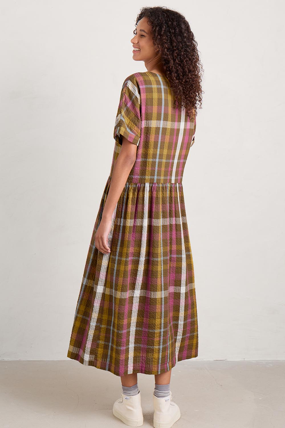 A model wearing the Brouse Dress in colour Clover (Green), from the back