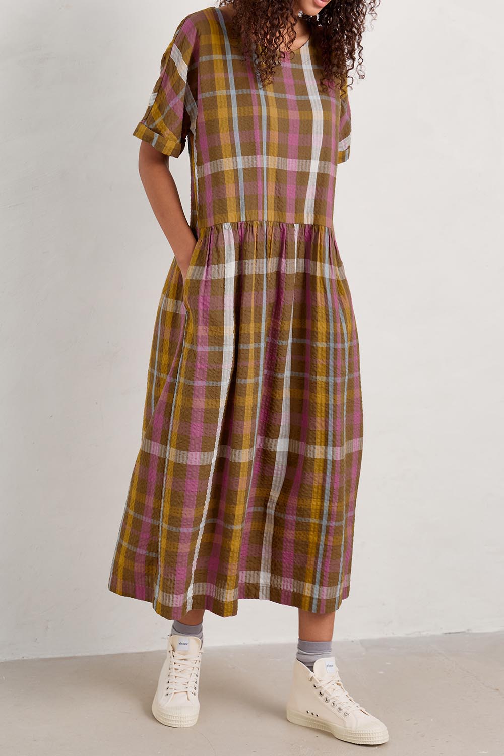 A model wearing the Brouse Dress in colour Clover (Green), from the front, cropped image