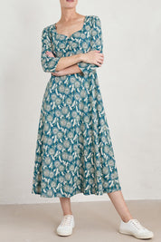 A model wearing the Three Quarter Secret Cove Dress in colour Dandelion (Blue), from the front, cropped image