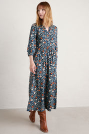 A model wearing the Fox Page Dress in colour Bloom (Blue), from the front, showing the whole outfit