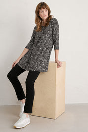 A model wearing the Arusha Tunic in colour Leaves (Black), from the front, showing the whole outfit